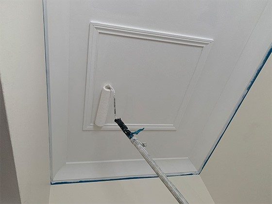 Using a paint roller to paint the ceiling